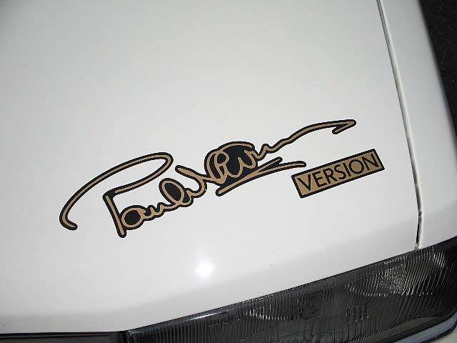 Paul Newman teve até escuderias, por onde passaram nomes que viriam a se consagrar na Fórmula 1, como Keke Rosberg e Nigel Mansell. Newman era tão apaixonado por carros que olha só a marca registrada dele num dos modelos (foto)