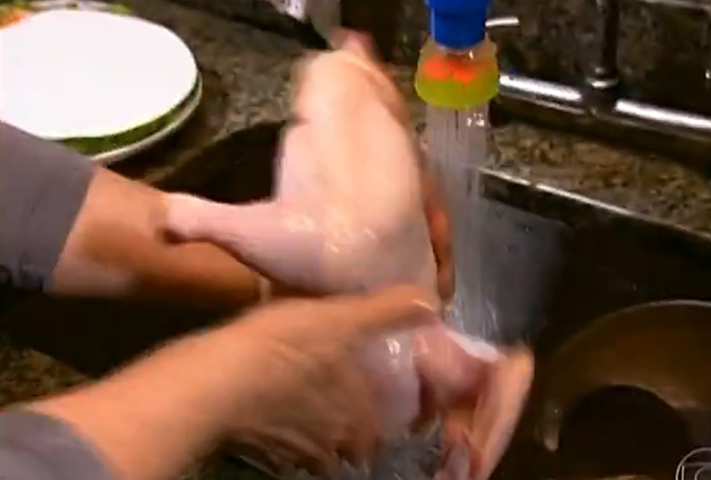 ERRO 2 - Lavar o frango na pia: quando a pessoa lava o frango, gotas de água podem respingar no pano de prato, em utensílios usados para o preparo das refeições ou, ainda, nos próprios alimentos que serão consumidos. Essas gotas podem carregar bactérias, causando o risco de contaminação da refeição.  -- Reprodução / GShow/Fantastico