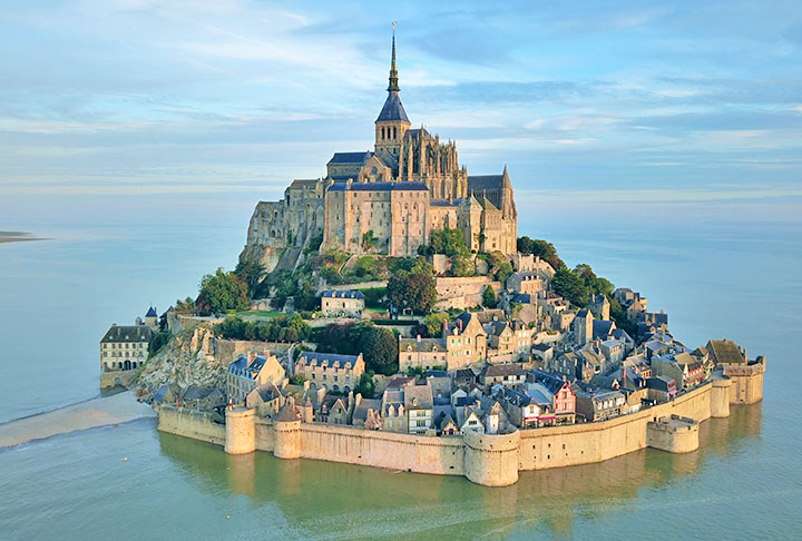 MONTE SAINT-MICHEL - Ã? uma ilha rochosa, cerca por muralhas, na regiÃ£o da Normandia, na FranÃ§a. No decorrer da Guerra dos Cem anos foi uma defesa impenetrÃ¡vel, pois todas as tentativas inglesas de tomÃ¡-la foram fracassadas. Assim, virou um sÃ­mbolo do nacionalismo francÃªs e foi utilizada como prisÃ£o durante a RevoluÃ§Ã£o Francesa.