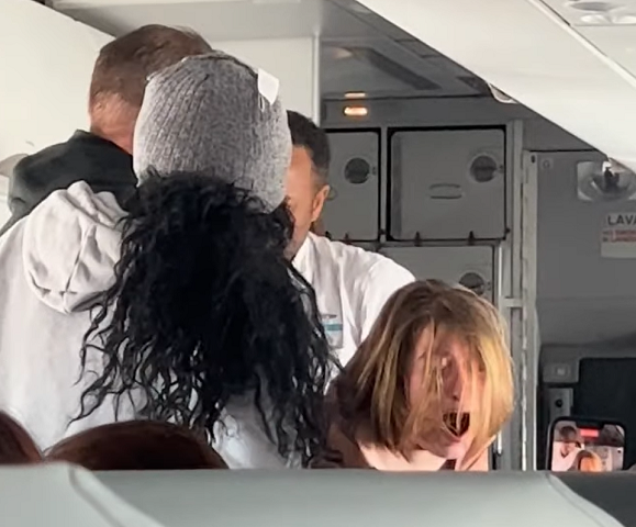 O vídeo caótico exibe a mulher de cabelos curtos berrando e gemendo de maneira desordenada, enquanto membros da tripulação e outros passageiros tentam contê-la.