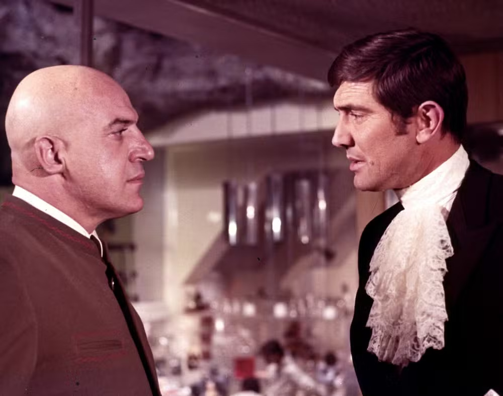 Lazenby ganhou fama ao interpretar o agente secreto James Bond em "007 A Serviço Secreto de Sua Majestade", em 1969. É o único ator que viveu o personagem apenas uma vez. Mas o papel alçou sua carreira na época. Na foto, ele (direita) em cena com Telly Savallas. 