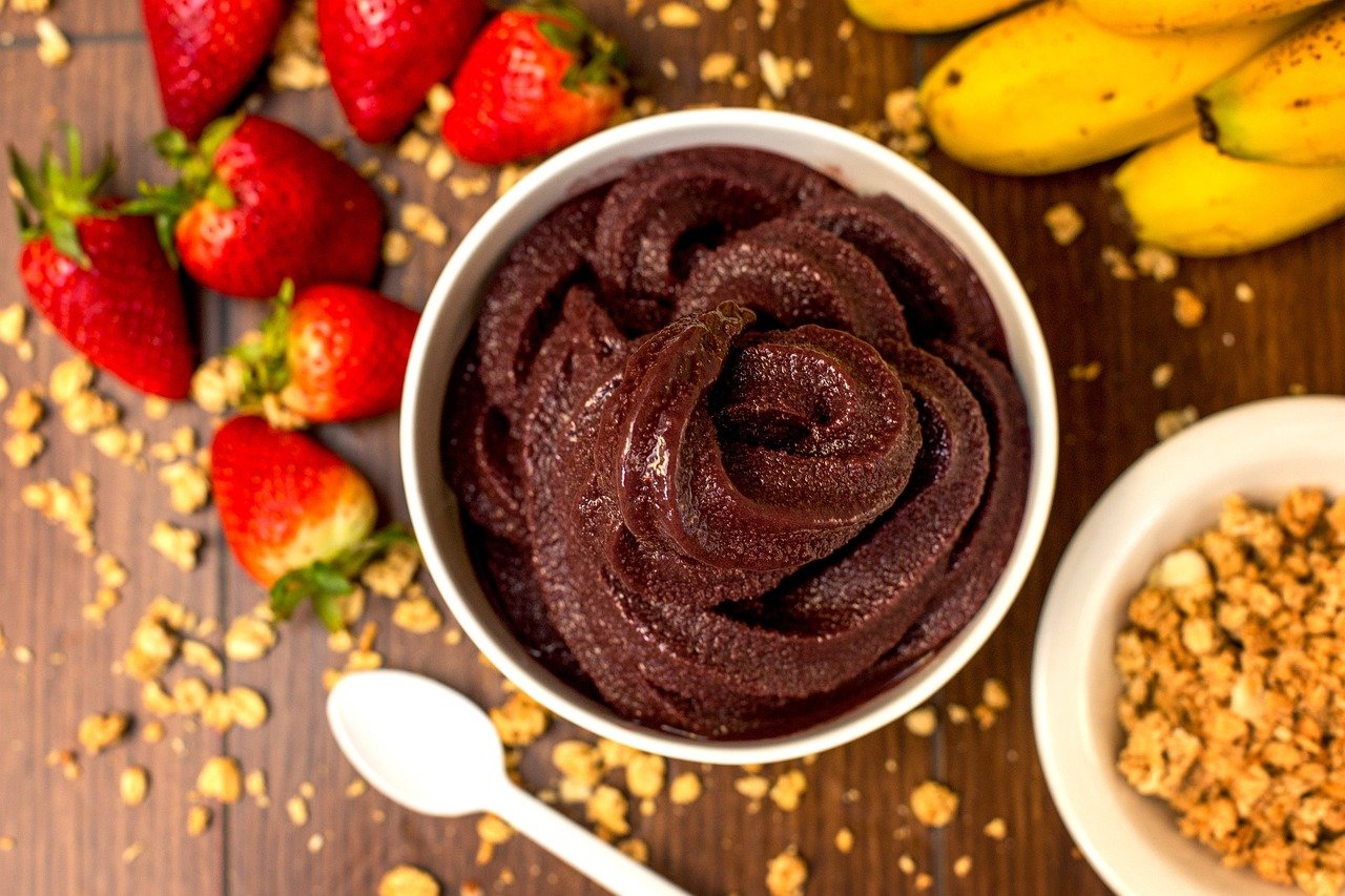 Açaí – Fonte de carboidratos, gorduras e compostos antioxidantes, pode ajudar na reposição de energia, especialmente após atividades físicas. O valor nutricional varia conforme os acompanhamentos. Para uma opção mais equilibrada, convém evitar o excesso de xaropes, açúcar e leite condensado.