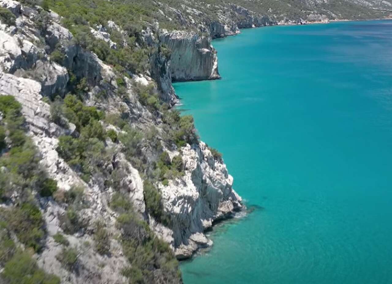 Com suas águas cristalinas e formações rochosas impressionantes, Cala Luna é uma das praias mais icônicas da Sardenha. Este paraíso escondido, acessível apenas por barco ou por uma trilha desafiadora, é ideal para nadar, praticar snorkeling e admirar a beleza intocada da natureza.-Youtube/Sardegna World 