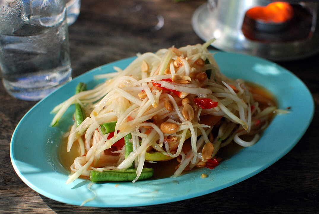 Tailândia - Som Tam (Salada de Mamão Verde): Uma salada refrescante e extremamente picante, feita com pimentas vermelhas, mamão verde ralado, molho de peixe e amendoim.
