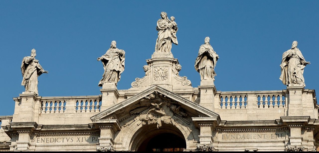 A Basílica de Santa Maria Maggiore tem arquitetura que mistura estilos paleocristão, românico, barroco e renascentista. Sua imponente fachada do século XVIII exibe colunas e belas esculturas no alto, representando santos e figuras religiosas. A torre sineira é a mais alta de Roma, com 75 metros.