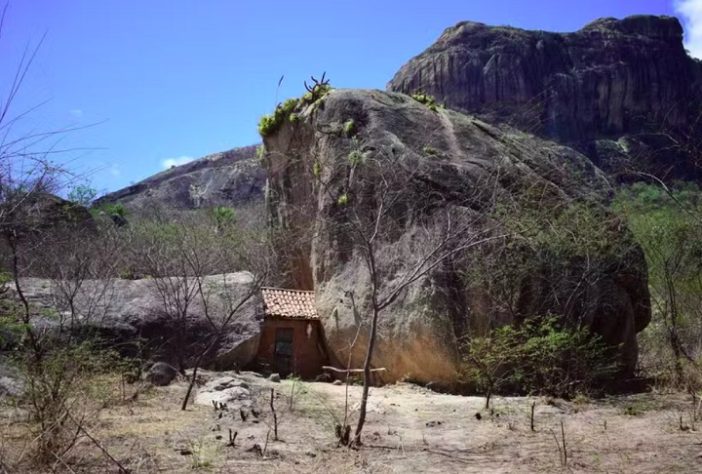 Casinha minúscula espremida entre duas rochas gigantes chama a atenção em distrito do Ceará