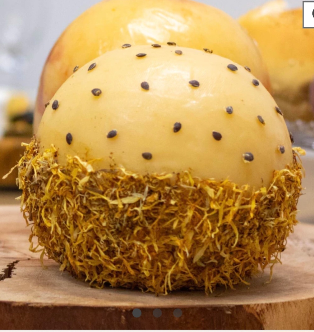 Ele tem uma casca decorada com sementes de maracujá na parte superior e flores comestíveis na base, resultando num visual exuberante e um aroma surpreendente . Quem olha pela primeira vez nem diz que é queijo.