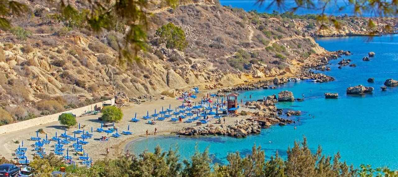 Konnos Bay: cercada por floresta de pinheiros, com águas calmas e quentes, perfeita para famílias e esportes aquáticos.