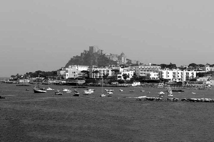 Um vislumbre da cidade de Ísquia, capturado do mar, pouco antes da entrada do porto - Ischia, é uma comuna italiana da região da Campânia, província de Nápoles - Domínio Público/Wikimédia Commons