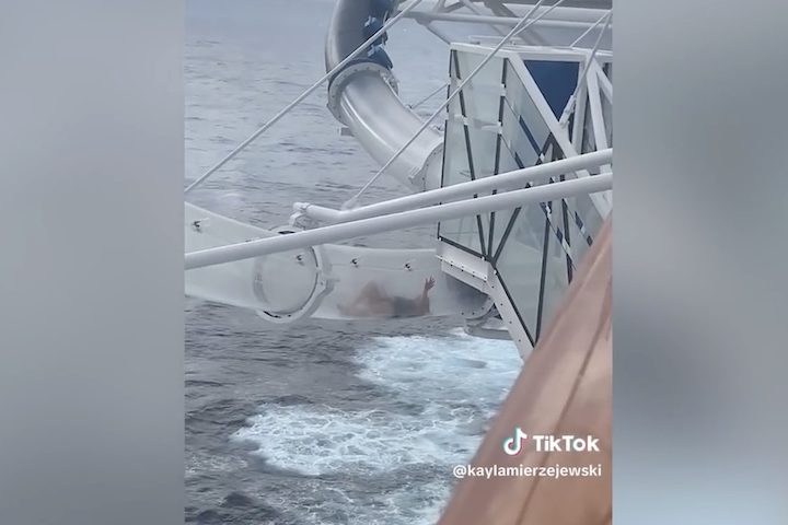 Ela aparece tentando se apoiar com as mãos nas paredes do escorregador, sem conseguir se mover para frente.