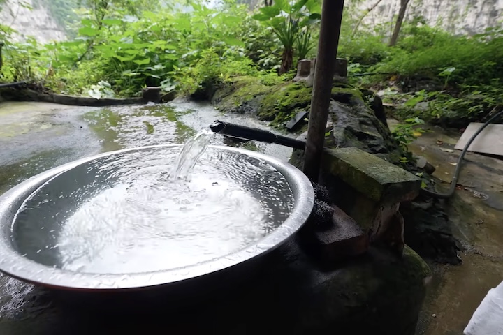 A água vem de uma nascente canalizada diretamente da encosta, fornecendo abastecimento contínuo e limpo. 