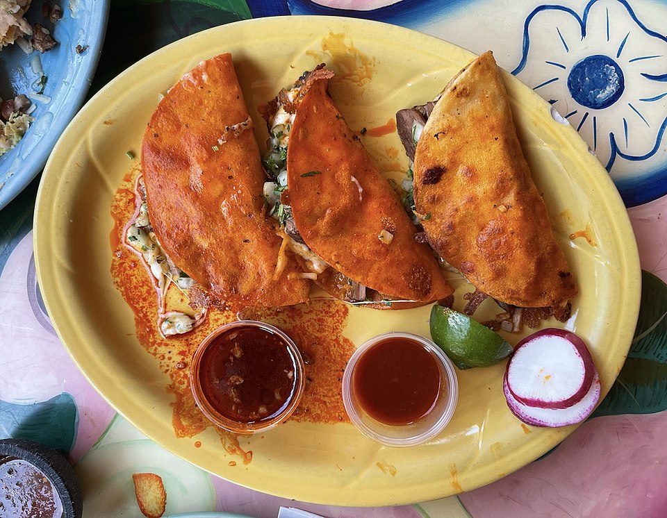 4º lugar – Quesabirria (México). Tortilhas recheadas com carne de birria cozida lentamente, queijo derretido e caldo para mergulhar, virando febre nas ruas mexicanas.