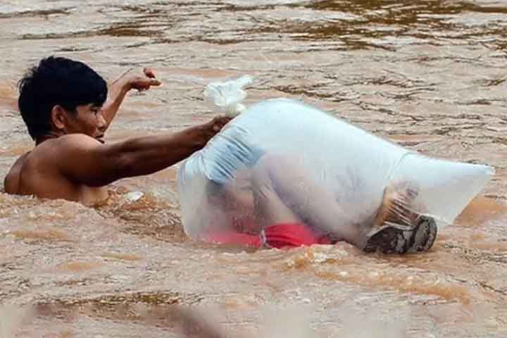 Em Huoi Ha pais colocam os filhos dentro de sacolas de nylon para cruzar o rio Nam Chim - Reprodução do Youtube canal Speedy Facts