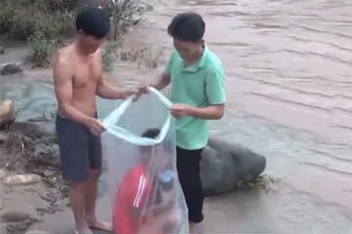 Em Huoi Ha pais colocam os filhos dentro de sacolas de nylon para cruzar o rio Nam Chim - Reprodução do Youtube canal @Quicknews.20