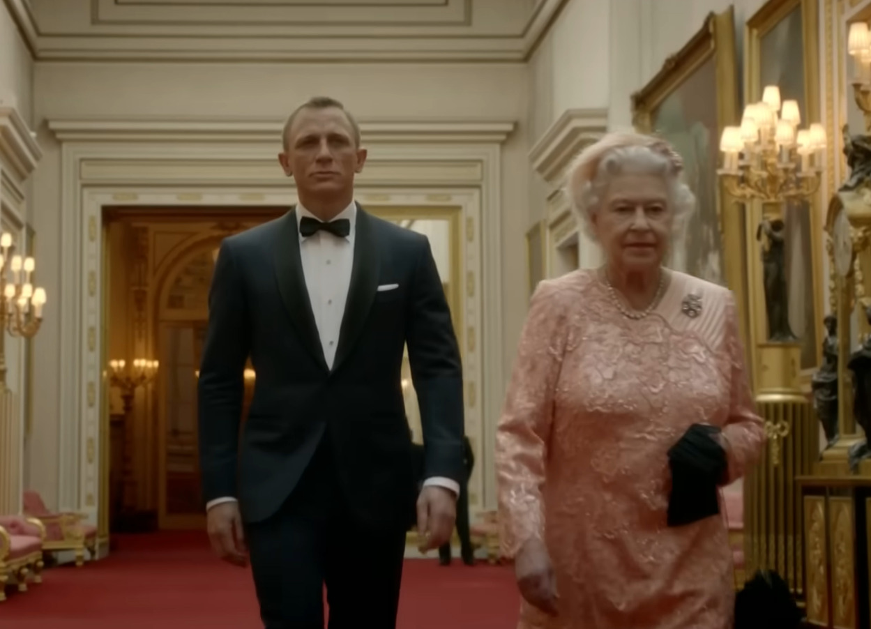 <p>Craig protagonizou um dos momentos mais marcantes da cerimônia de abertura das Olimpíadas de Londres 2012 ao aparecer como James Bond no curta “Happy and Glorious”. No vídeo, o agente chega ao Palácio de Buckingham para escoltar a rainha Elizabeth II até o Estádio Olímpico. Em uma cena icônica, a monarca o cumprimenta com “Boa noite, Sr. Bond”, e, na sequência final, ambos aparecem saltando de paraquedas de um helicóptero com a bandeira do Reino Unido sobre o estádio.</p>
