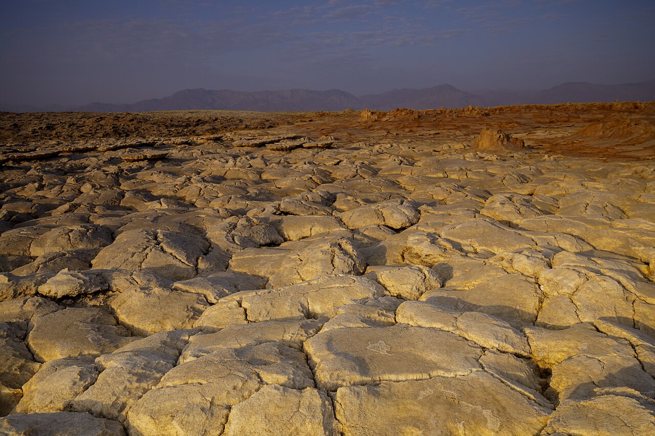 Situada no Deserto de Danakil, entre Etiópia, Eritreia, Djibuti e o Mar Vermelho, a região é descrita como “o lugar mais parecido com o inferno”. O calor extremo e os vapores tóxicos criam um ambiente hostil, mas ao mesmo tempo fascinante, onde a geologia revela processos únicos e contínuos.