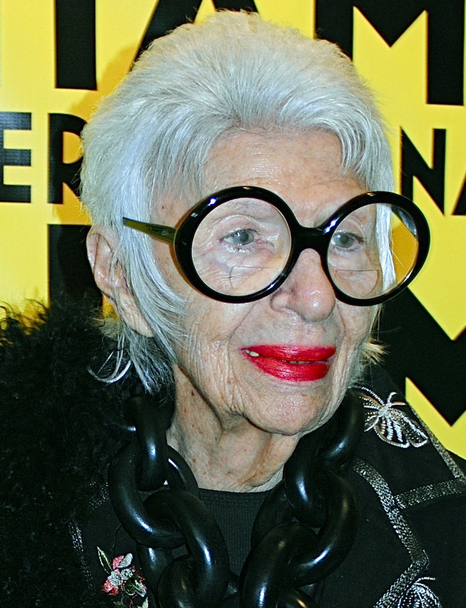 <p>Iris Apfel, empresária e ícone da moda que inspira a peça, nasceu em 1921, no Queens, em Nova York, e faleceu em 2024, aos 102 anos. Tornou-se referência internacional pelo visual exuberante, pelos posicionamentos ousados e pelo estilo maximalista, marcado pelos grandes óculos redondos e por um senso de humor irreverente.</p>
