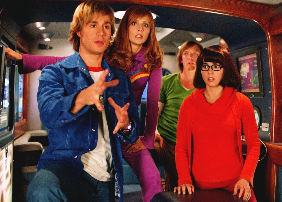 “Scooby-Doo” recebeu sua primeira adaptação live-action em 2002, em um filme dirigido por Raja Gosnell, com roteiro de James Gunn e estrelado por Freddie Prinze Jr. como Fred, Sarah Michelle Gellar como Daphne, Matthew Lillard como Salsicha e Linda Cardellini como Velma. Scooby-Doo foi dublado por Neil Fanning e criado por efeitos especiais. Raja Gosnell e James Gunn voltaram a dirigir e escrever o roteiro e o elenco principal reprisou seus papéis.

