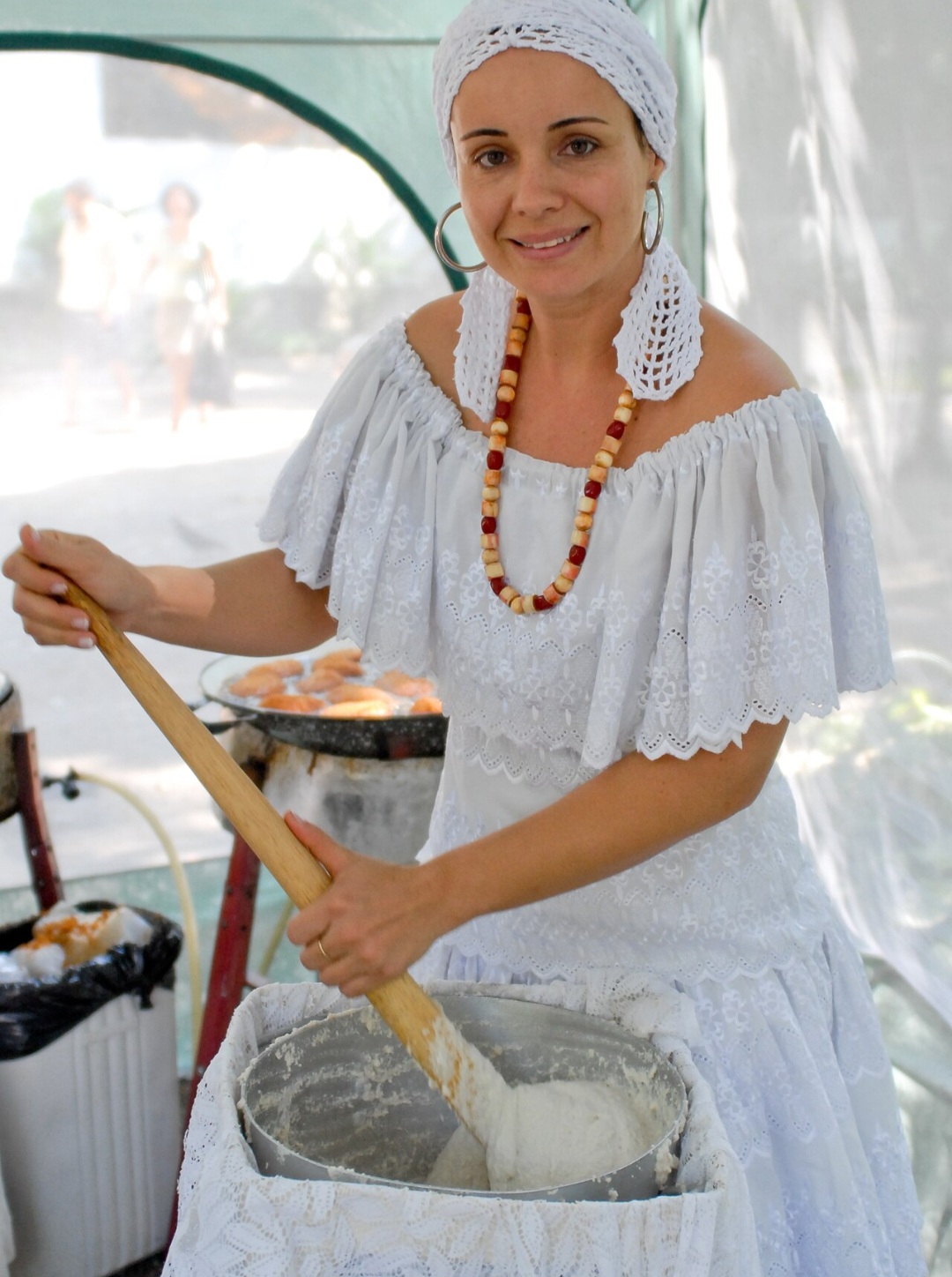 <p>E a roupa da baiana, não poderia ser diferente, é parte essencial do ofício. Saia rodada, pano da costa, turbante e fios de contas revelam a ligação com os orixás. Não há dúvidas: arrumar-se para vender acarajé é também vestir a ancestralidade.</p>
