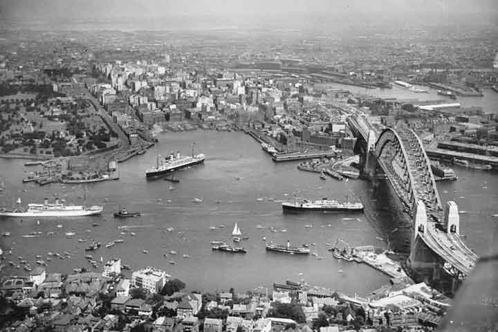 Sidney respira história e modernidade, e nada simboliza melhor essa união do que a Ponte da Baía da cidade, inaugurada em 19 de março de 1932. Completou 94 anos. Vamos revisitar não apenas sua grandiosa engenharia, mas a trajetória da cidade que cresceu ao seu redor, tornando-se um dos destinos mais vibrantes do mundo. -  (crédito: National Library of Australia/Wikimédia Commons)