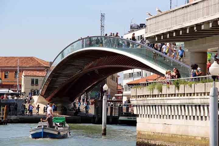 Também chamada de Ponte de Calatrava, liga a estação ferroviária de Santa Lucia à Piazzale Roma, funcionando como elo estratégico para quem chega à cidade. Sua estrutura de vidro e aço representa a tentativa de inserir tecnologia contemporânea na paisagem histórica. Apesar das críticas iniciais, tornou-se parte do cotidiano urbano e um marco da modernidade em meio ao patrimônio antigo.