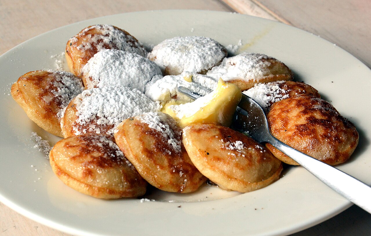 Os poffertjes são pequenas panquecas fofinhas feitas com fermento e farinha de trigo sarraceno. Servidos com manteiga e açúcar de confeiteiro, são presença obrigatória em feiras e festas populares. Sua textura leve e sabor delicado remetem à infância e ao ambiente festivo, tornando-os uma das sobremesas mais queridas do país.