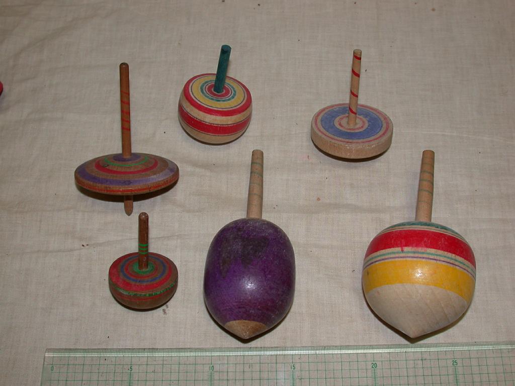 No entanto, existem vários tipos de pião, que variam em tamanho, formato e material. Esse pião de madeira tradicional é o mais comum, mas há versões maiores, menores e até mais achatadas, que oferecem maior estabilidade. Também existem modelos com pontas diferentes, como arredondadas ou afiadas, que influenciam no modo de girar. Ainda há versões modernas feitas de plástico e outros materiais, como cerâmica, pedra, bambu e terracota. Apesar das variações, o formato básico permanece o mesmo, sempr