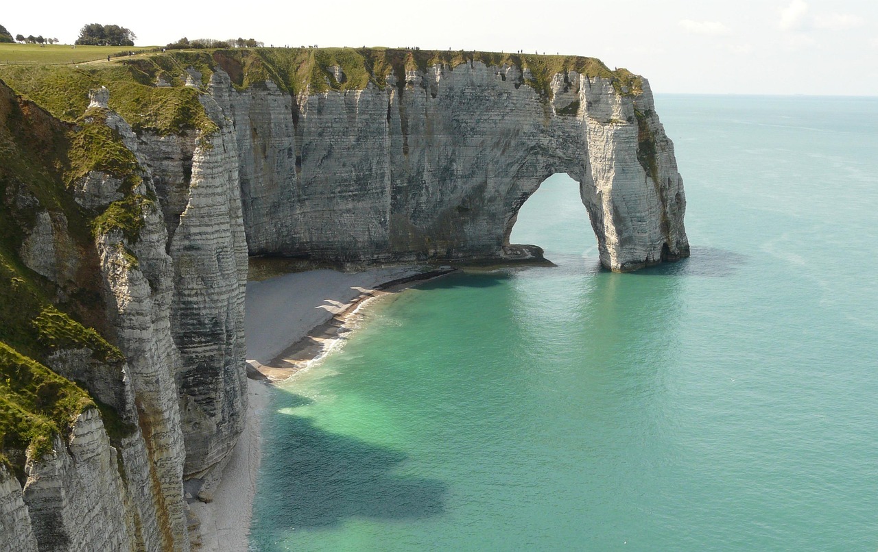 A trilha mais famosa leva à falésia d’Aval, marcada por um imenso arco natural esculpido pelo mar ao longo dos séculos. A formação parece um elefante e se tornou cartão-postal da cidade e símbolo mundial de Étretat. Sua imponência impressiona tanto de perto quanto vista do alto, reforçando a força da erosão.