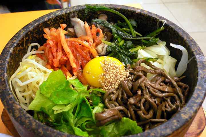O bibimbap é um dos pratos mais emblemáticos da culinária da Coreia do Sul. Ele representa de maneira quase simbólica a tradição gastronômica coreana de equilibrar sabores, cores, texturas e nutrientes em uma única refeição. O nome deriva da junção das palavras coreanas “bibim”, que significa “misturar”, e “bap”, que quer dizer “arroz cozido”. A proposta do prato é simples: reunir diferentes ingredientes sobre uma base de arroz branco e misturá-los antes de comer. O resultado, porém, está longe  -  (crédito: - abex/Wikimédia Commons)