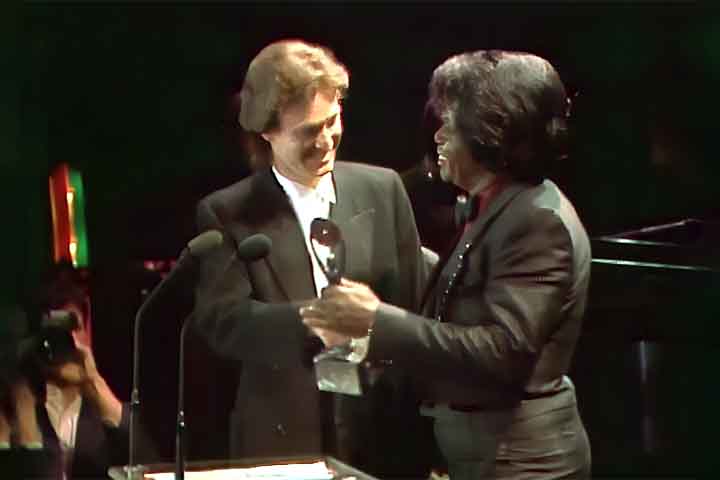 James Brown foi um dos primeiros dez artistas a entrar no Salão da Fama do Rock and Roll, em 1986, reconhecimento que destacou sua importância histórica. Recebeu o Grammy pelo conjunto da obra em 1992 e a honraria do Kennedy Center em 2003, acumulando prêmios de prestígio. Esses reconhecimentos oficiais consolidaram sua posição como ícone cultural global, reverenciado em todo o mundo.