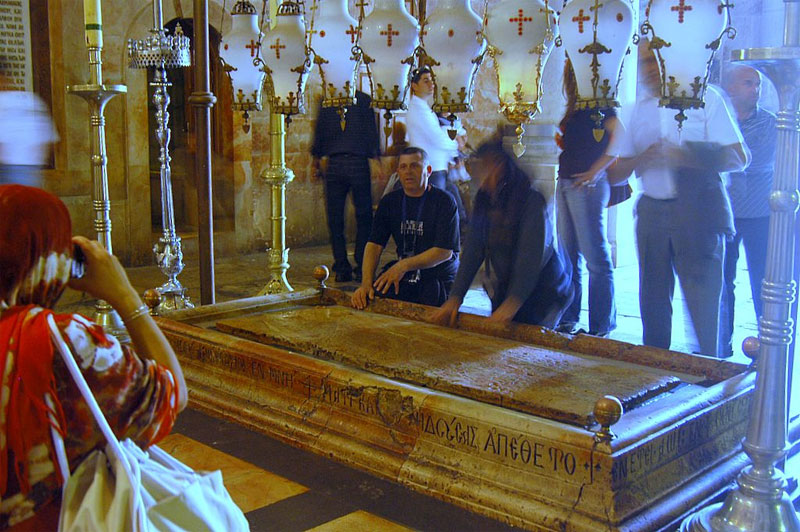 A Pedra da Unção, situada próxima à entrada, é onde, segundo a tradição, o corpo de Jesus foi preparado para o sepultamento, tornando-se um dos pontos mais simbólicos do templo. Visitantes costumam tocar ou ungir a pedra com óleos e tecidos como gesto de fé e reverência, e o brilho da superfície reflete séculos de devoção acumulada. A grande maioria, alias, leva lembranças impregnadas com o óleo sagrado.