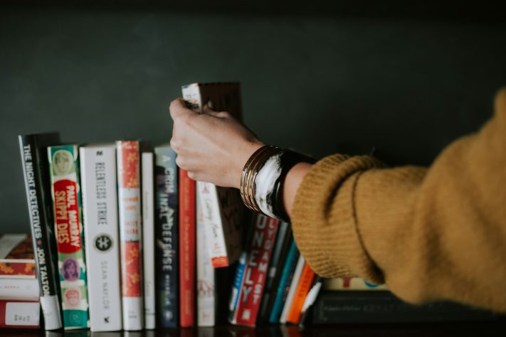 Mulher pegando livro na estante – Christin Hume/Unsplash