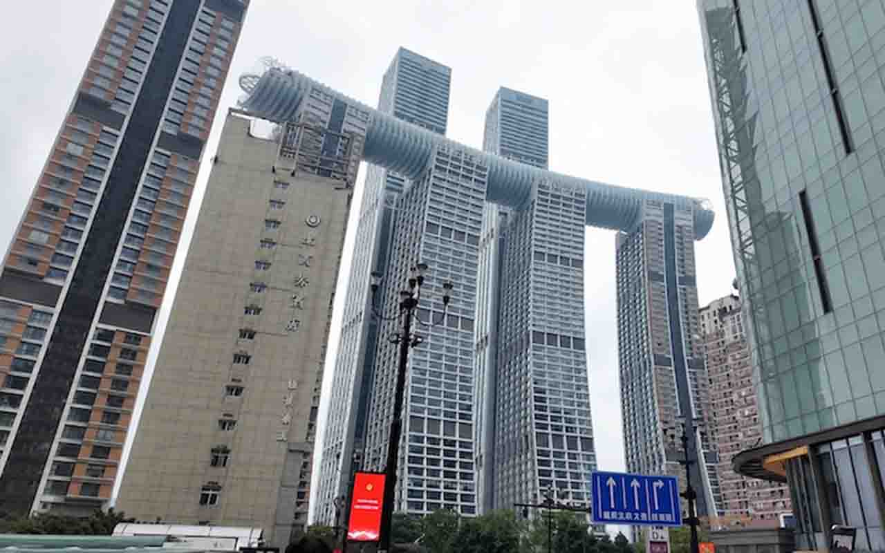 A engenharia civil contemporânea ganhou um novo marco com a conclusão de uma estrutura monumental na China, que desafia os conceitos tradicionais de verticalidade urbana. Isso porque, na metrópole de Chongqing, que abriga mais de 30 milhões de habitantes, foi erguido um complexo arquitetônico denominado 'Raffles City', cujo principal diferencial é um edifício de formato horizontal que se estende por 300 metros de comprimento. Batizado de 'The Crystal', o gigantesco arranha-céu conecta quatro tor -  (crédito: Reprodução/YouTube Singapore City Walks)