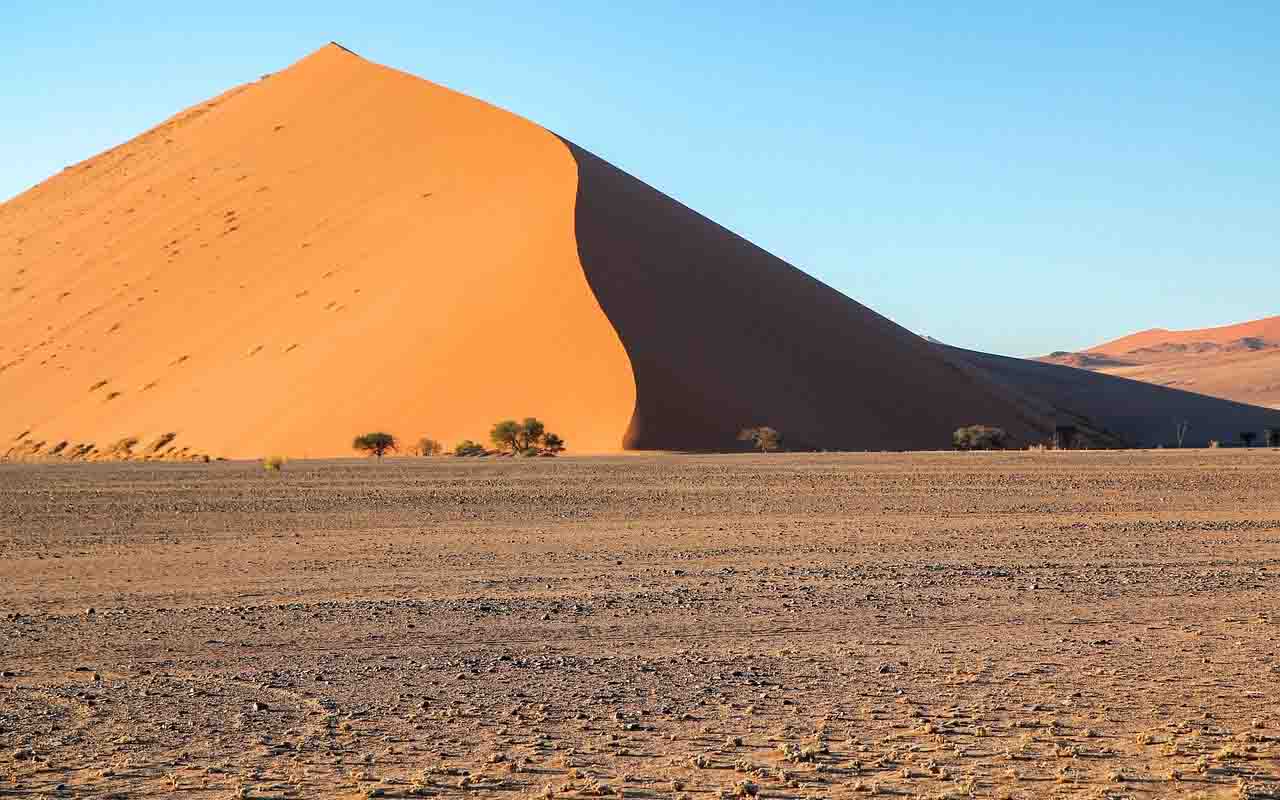 As dunas de Sossusvlei impressionam por sua altura, estando entre as maiores do mundo – frequentemente acima de 200 metros. Com cores que variam entre o vermelho e o laranja, resultado da oxidação do ferro presente no solo, elas criam um espetáculo visual que muda conforme a luz do sol. Assim, cada amanhecer e entardecer transforma a paisagem em um desenho vivo, marcada por contrastes intensos.

