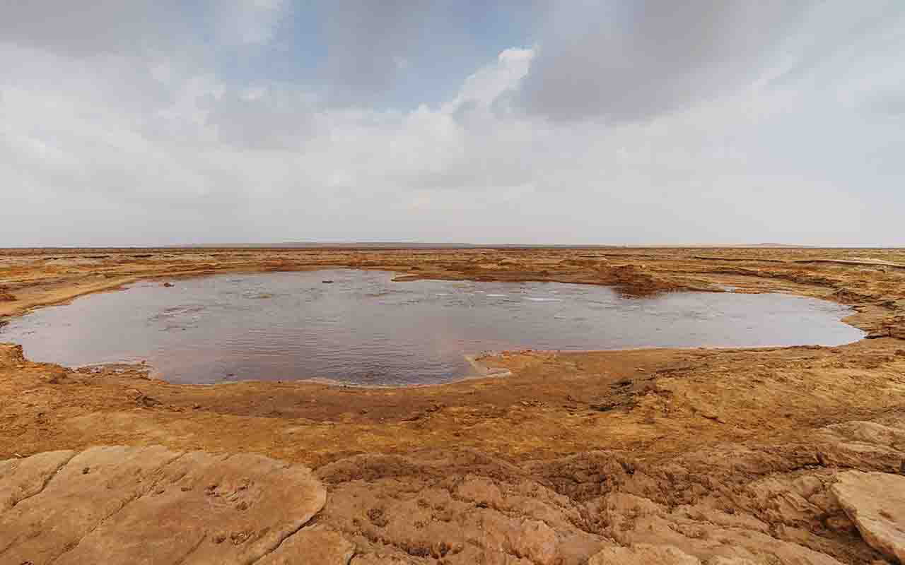 O campo hidrotermal de Dallol é o ponto mais emblemático da região. Ali, fontes termais jorram salmoura supersaturada que cristaliza em formas brancas, amarelas e vermelhas. A acidez das águas é brutal, chegando a ser milhares de vezes mais intensa que a de um limão, criando um ambiente quase alienígena.