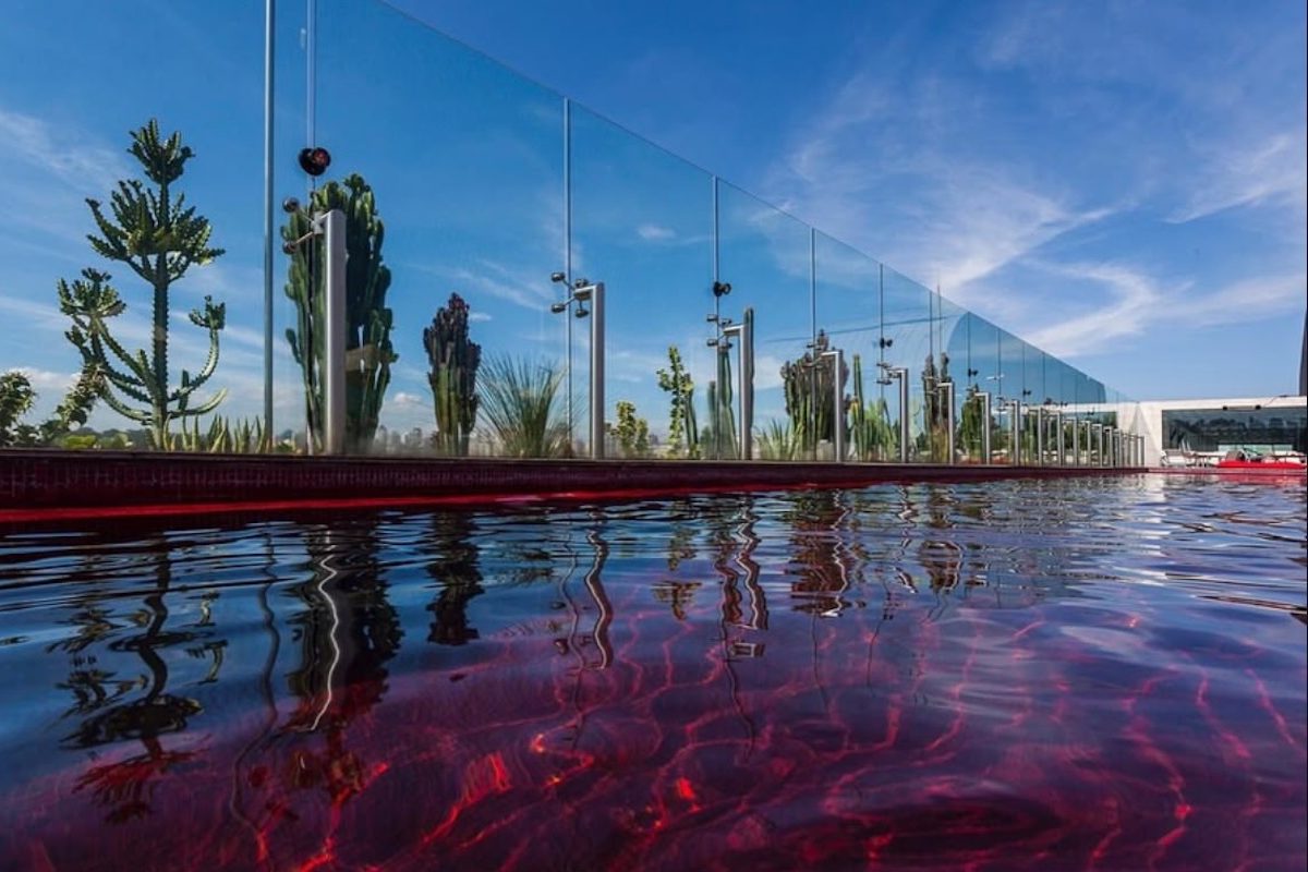 A piscina vermelha instalada no local tornou-se uma marca registrada do empreendimento e cria um forte contraste com o cenário urbano ao redor. Além disso, a ausência de guarda-corpos aparentes e a integração com o deque de madeira ampliam a sensação de que o ambiente paira acima dos prédios da cidade.