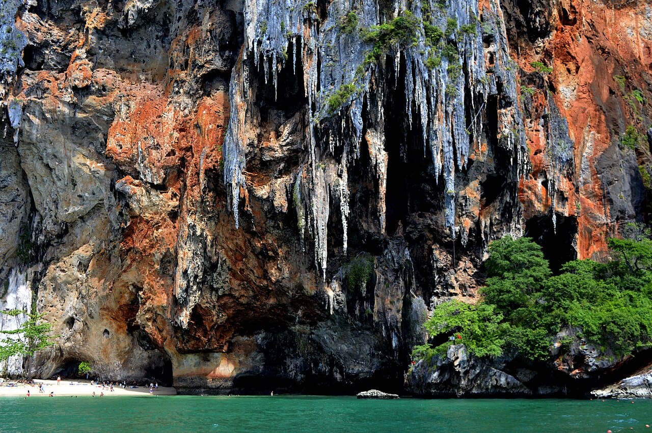 Railay Beach é acessível apenas por barco, o que já cria uma atmosfera de exclusividade e aventura. Suas falésias de calcário atraem escaladores do mundo inteiro, enquanto a areia branca e o mar azul oferecem descanso para quem busca tranquilidade. A combinação de esportes radicais e relaxamento faz da praia um destino versátil, capaz de agradar tanto aventureiros quanto viajantes em busca de paz. Ademais, o pôr do sol em Railay é considerado um dos mais belos da Tailândia, coroando cada dia com