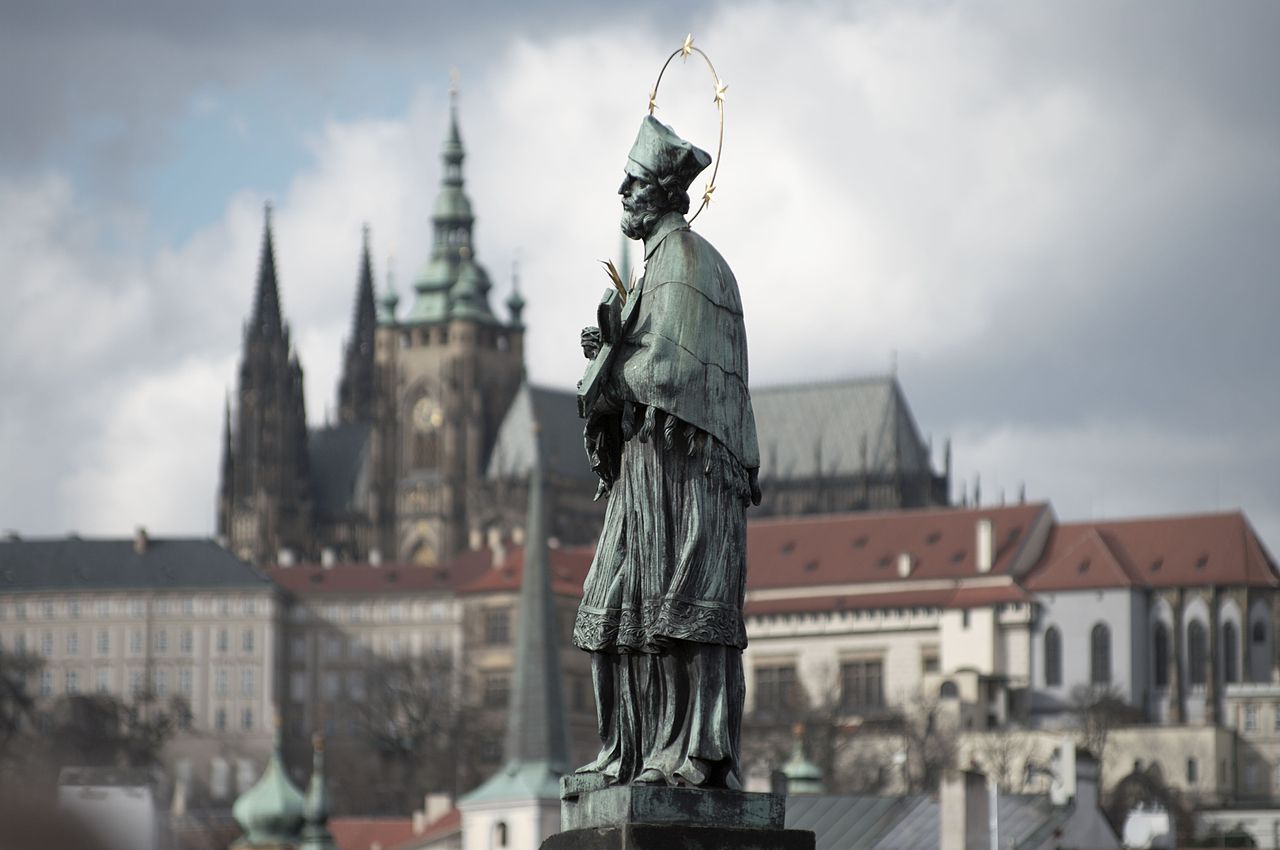 A Ponte Carlos, construída entre 1357 e 1402 sobre o Rio Moldava, é um dos monumentos medievais mais bem preservados da Europa Central e o cartão-postal mais famoso de Praga, capital da Tchéquia. Ao longo de suas muretas encontram-se 30 estátuas barrocas. Entre elas, a de São João Nepomuceno se destaca por ser a mais antiga e, possivelmente, a mais venerada. Fundida em 1683, ela foi a primeira escultura instalada na ponte e hoje é reconhecida como Patrimônio Mundial da Humanidade da UNESCO. 
 -  (crédito:  Wikimedia Commons / Bjorn Erik Pedersen )