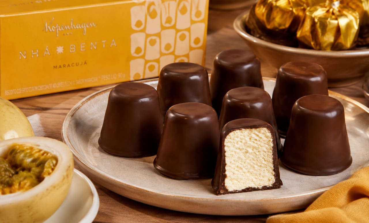 Com sua combinação de marshmallow macio, cobertura de chocolate e, em muitas versões, uma base de biscoito ou wafer, a nhá-benta conquistou gerações de brasileiros. Presente em confeitarias e chocolaterias há décadas, o doce continua despertando a curiosidade tanto pelo sabor quanto pela textura característica. Conheça algumas curiosidades sobre esse clássico da confeitaria. -  (crédito: imagem gerada por i.a 
)