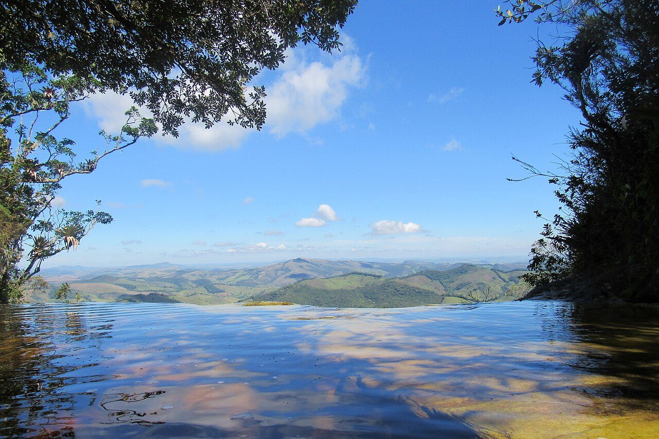 A natureza completa o cenário que atrai visitantes de todo o país. O Parque Estadual do Ibitipoca concentra atrações famosas, como a 'Janela do Céu', o 'Cruzeiro' e o 'Paredão de Santo Antônio', enquanto a Serra do Ibitipoca, reconhecida como monumento estadual, reforça o valor ambiental da região. -  (crédito: Wikimedia Commons/Humberto Alves de Vasconcelos Lima)