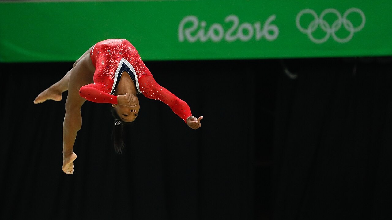 Simone Biles é uma atleta norte-americana considerada uma das maiores ginastas da história da modalidade. Dona de múltiplos títulos mundiais e olímpicos, ela se tornou referência mundial pela dificuldade técnica de suas rotinas, várias delas batizadas com seu próprio nome. 
