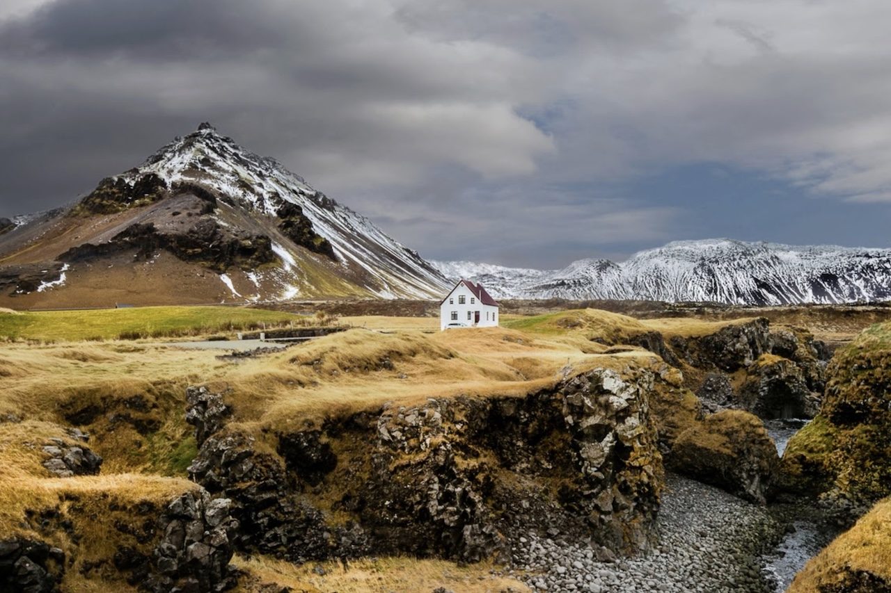 Arnarstapi, Islândia: Arnarstapi é um pequeno vilarejo da Península de Snæfellsnes, na Islândia, com cerca de 60 habitantes. Cercado por paisagens vulcânicas e localizado aos pés do vulcão Snæfellsjökull, o local se destaca por uma casa solitária de telhado vermelho que reforça o clima de isolamento e tranquilidade da região.