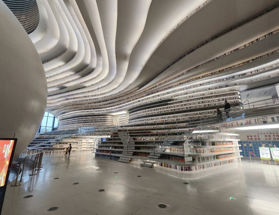 Ao atravessar suas portas, a sensação é de entrar em outro mundo. A “caverna de livros” tem cinco andares e cerca de 33.700 m², com estantes curvas que se estendem do chão ao teto. Mas nem tudo é o que parece: parte dos livros visíveis é formada por imagens impressas nas prateleiras.